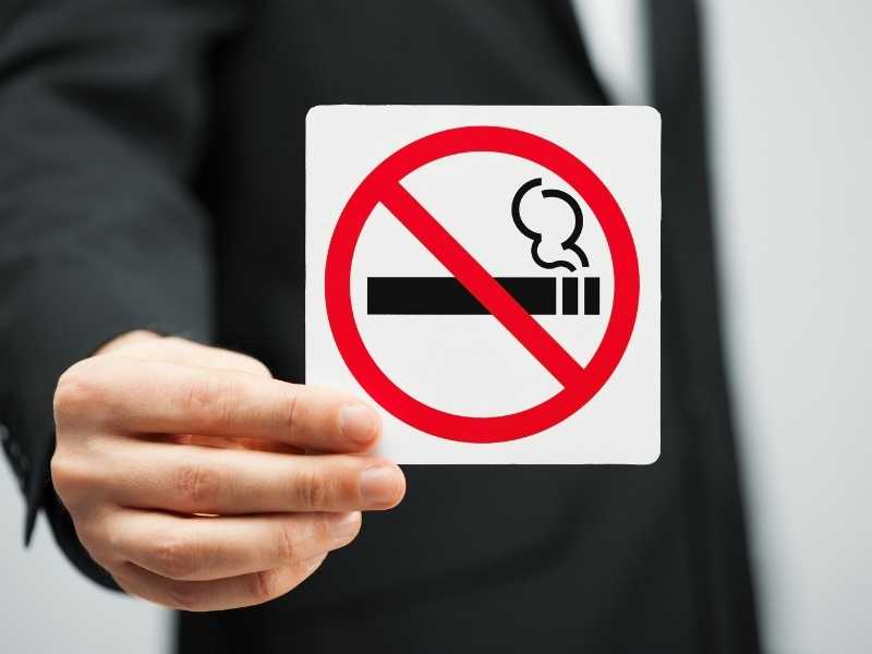 Άνθρωπος κρατάει πινακίδα για απαγόρευση καπνίσματος